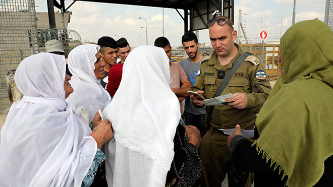 ضابط إسرائيلي يفحص وثائق النساء الفلسطينيات اللائي ينتظرن عند نقطة عبور عبر جدار الفصل الإسرائيلي
